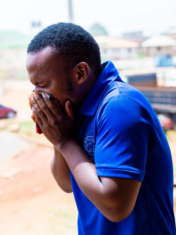 An African man coughing into his hand