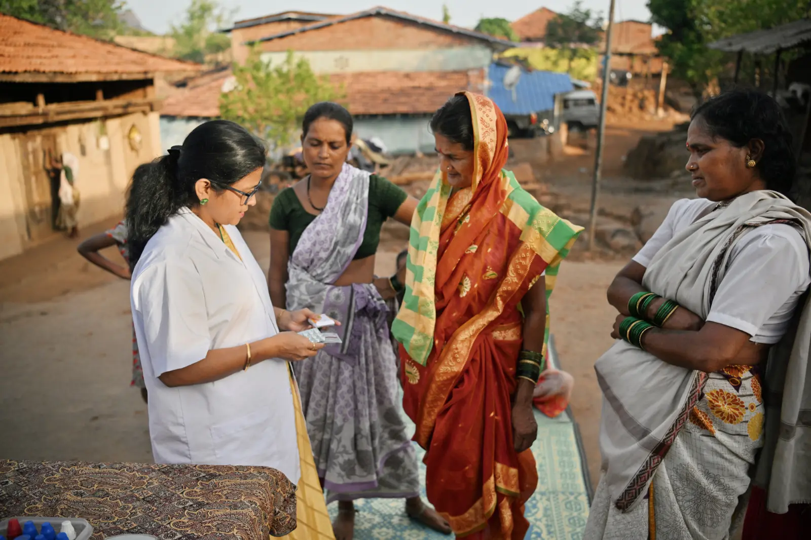 Epidemics That Didn't Happen: A doctor is explaining medication dosage to three women, in a sunny village