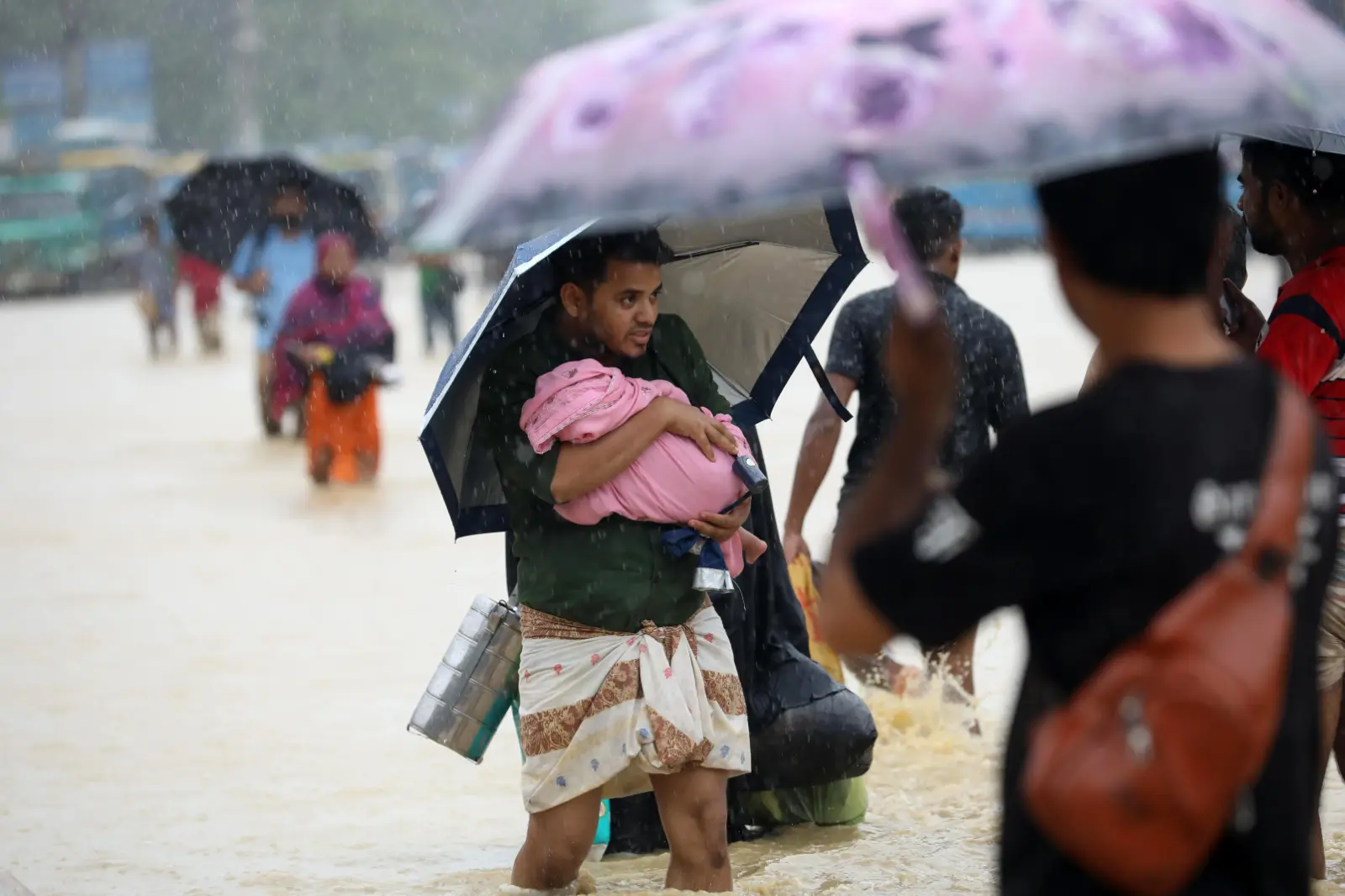 Epidemics That Didn't Happen: A man carries his small child through heavy rain and floods